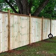 Wooden privacy fence in a yard with a black tire swing hanging near the right side.