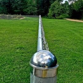 Chrome rail fence stretching into a green park with trees in the background
