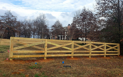 Wooden fence with diagonal cross-bracing in a leafless park under a cloudy sky