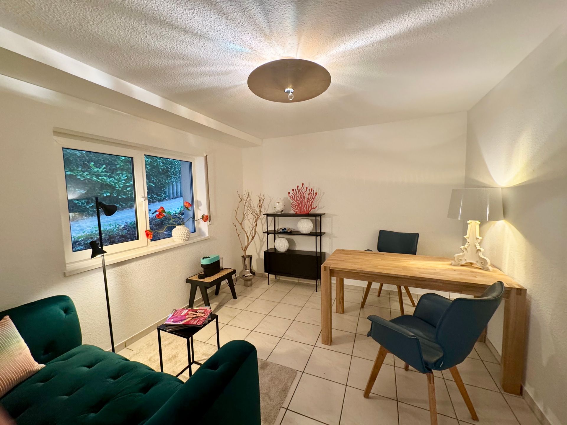 Ein Wohnzimmer mit Sofa, Tisch, Stühlen und Fenster.