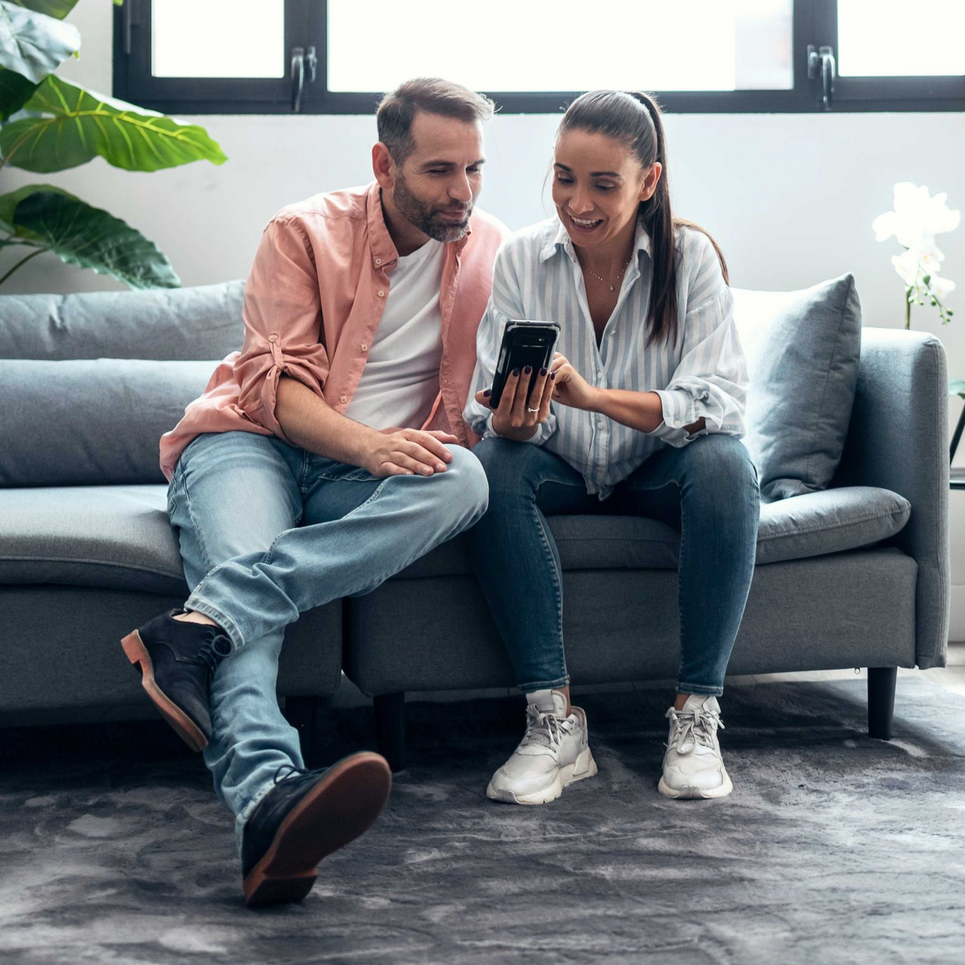 Couple crying on a couch while meeting with a therapist, who is taking notes.