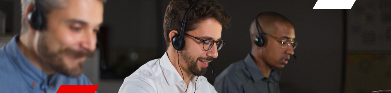 Três pessoas usando fones de ouvido em um call center, trabalhando em suas mesas.