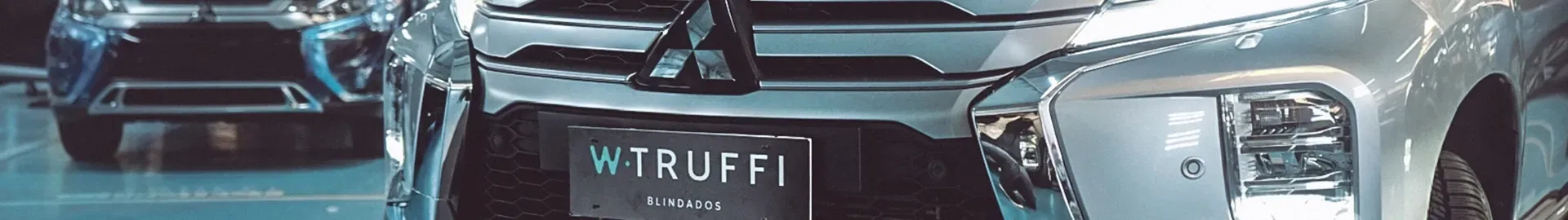 Carros em uma exposição de automóveis, um carro prateado com a frente visível e uma placa que diz