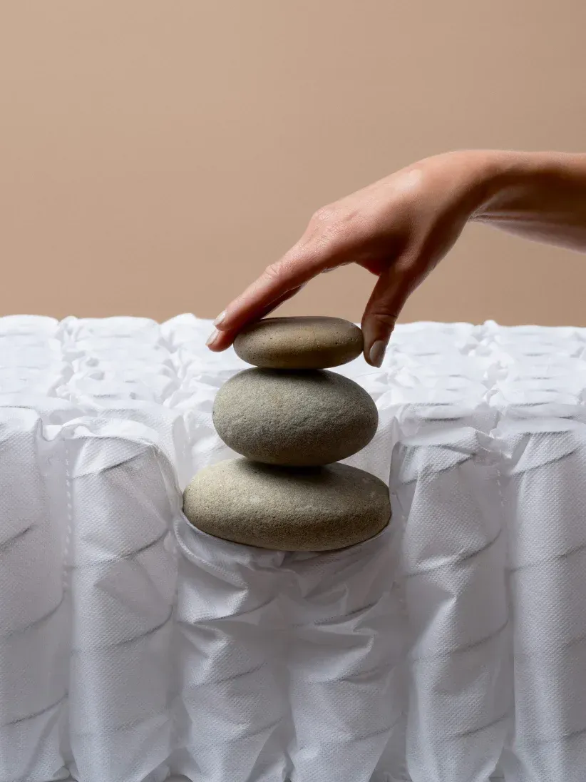 A person is stacking rocks on top of a mattress.