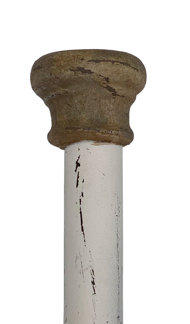 A close up of a white pipe with a brown top on a white background.