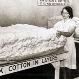 A black and white photo of a woman stacking cotton in layers