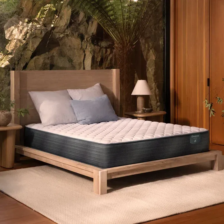 A bed with a mattress and pillows in a bedroom