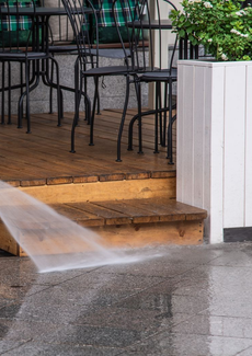Water spraying across a wet patio entrance with chairs and a white fence panel nearby