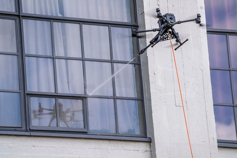 Window cleaner suspended by ropes beside a tall building’s glass windows