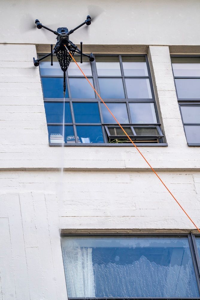 Drone with orange rope near a building window, viewed from outside