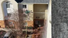 Residential courtyard with a drone hovering near a multi-story building and leafless trees