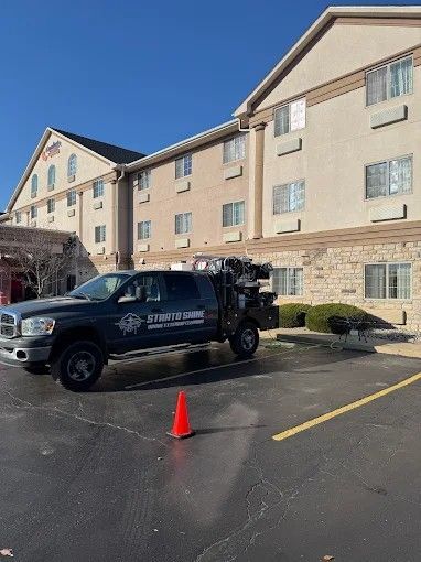 Black pickup truck and orange cone in a motel parking lot under a blue sky