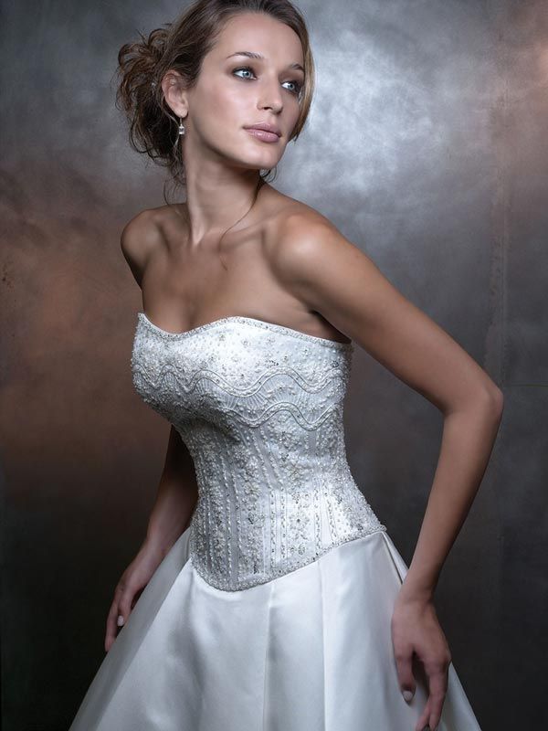 Woman in a white strapless dress posing against a gray studio backdrop