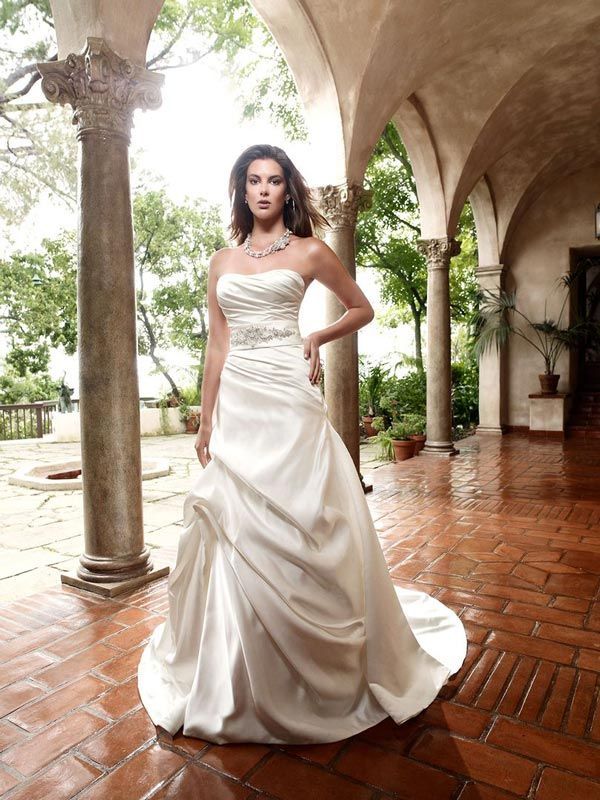 Woman in a white wedding gown standing in an arched courtyard with wet terracotta tiles and columns