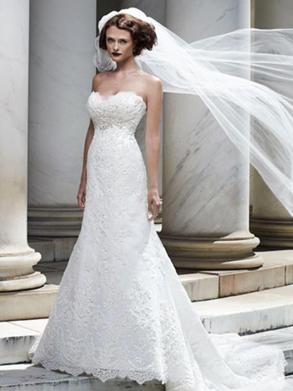 Bridal model in a lace white wedding gown with a long veil standing by marble columns
