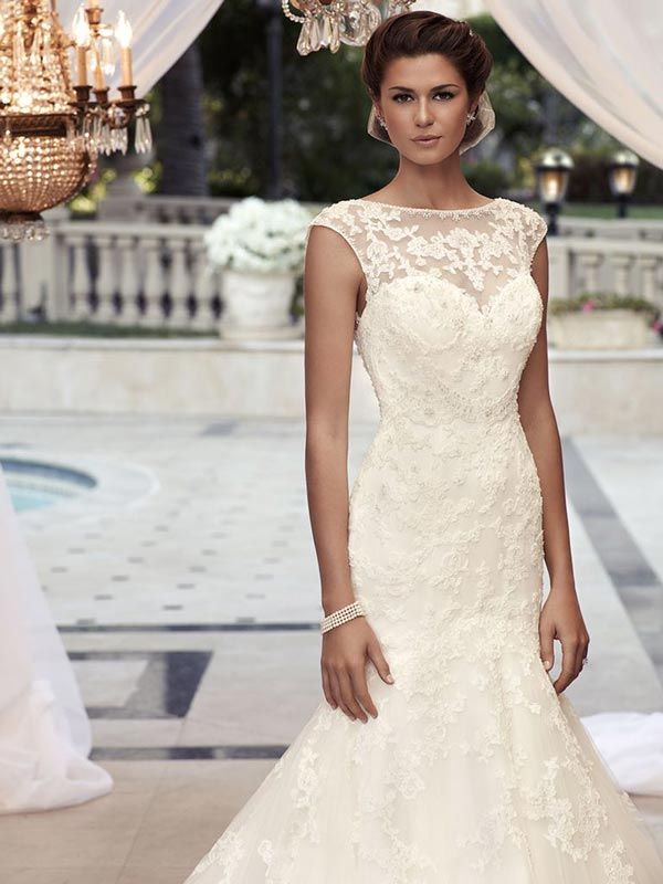 Woman in a white lace wedding gown standing in a chandelier-lit courtyard