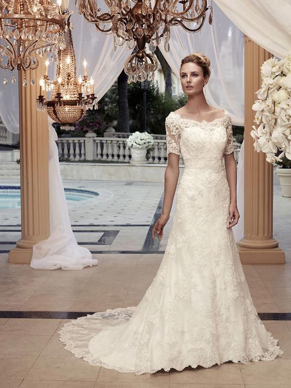 Woman in an ivory lace wedding gown standing in an elegant outdoor pavilion with chandeliers