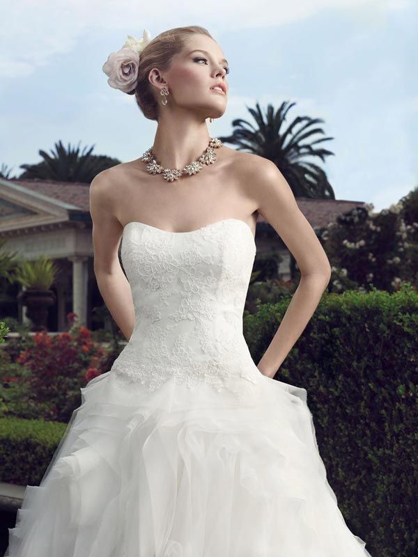 Woman in a strapless white gown posing outdoors in a garden setting