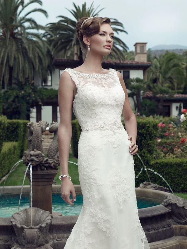 Woman in a white lace gown standing by a pool in a tropical garden