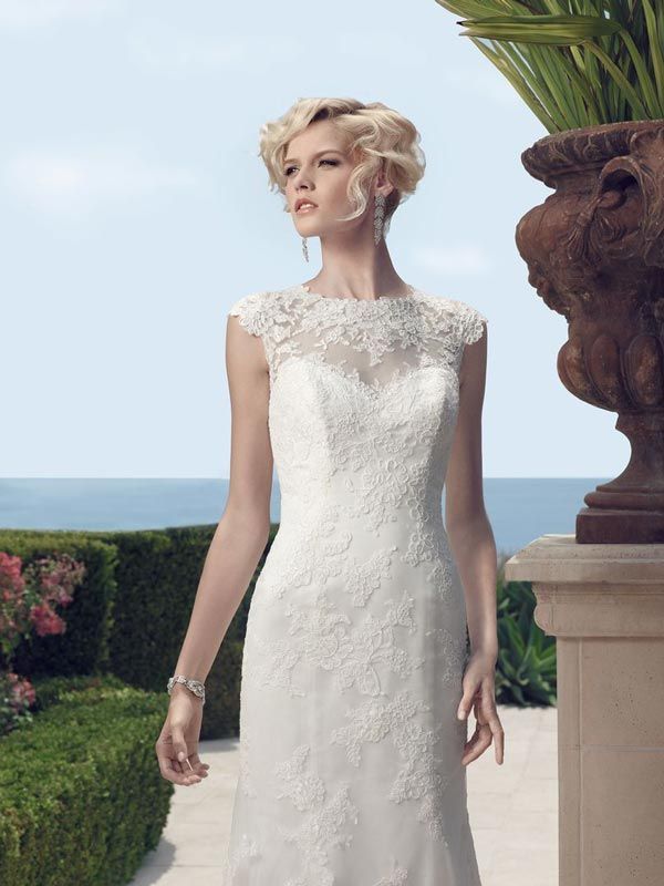 Woman in a white lace dress standing on a terrace by the sea.