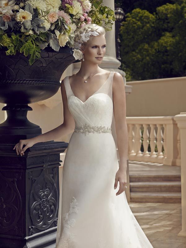Bride in a white gown beside a floral urn on a terrace staircase