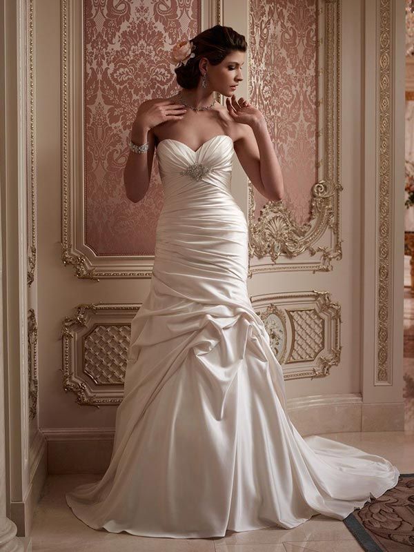 Bride in a white satin wedding gown standing in an ornate pink room with gold trim