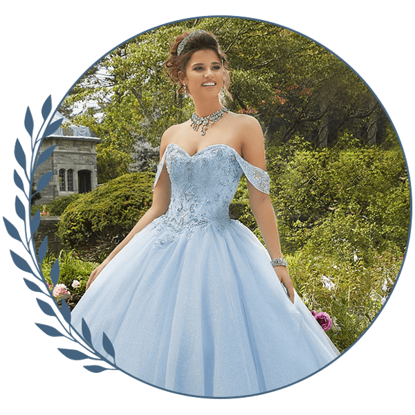 Woman in a light blue ball gown standing in a garden with trees and flowers