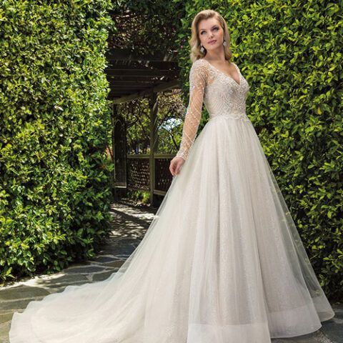 Bride in a white lace wedding gown standing in a leafy garden archway