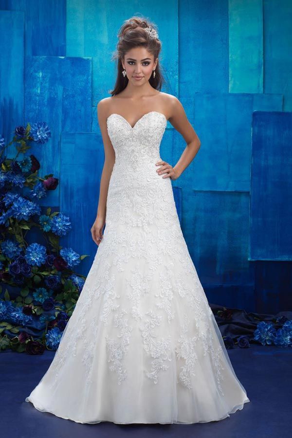 Woman in a strapless white wedding gown posing against a blue backdrop