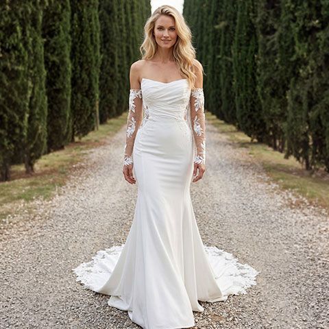 Bride in a white lace wedding gown standing in a leafy garden archway