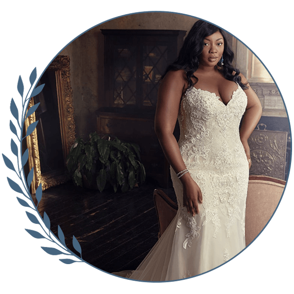 Bride in a white lace gown standing in a softly lit room beside a window