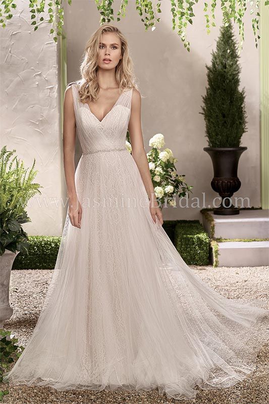 Bride in a sleeveless ivory lace wedding gown standing in a garden setting