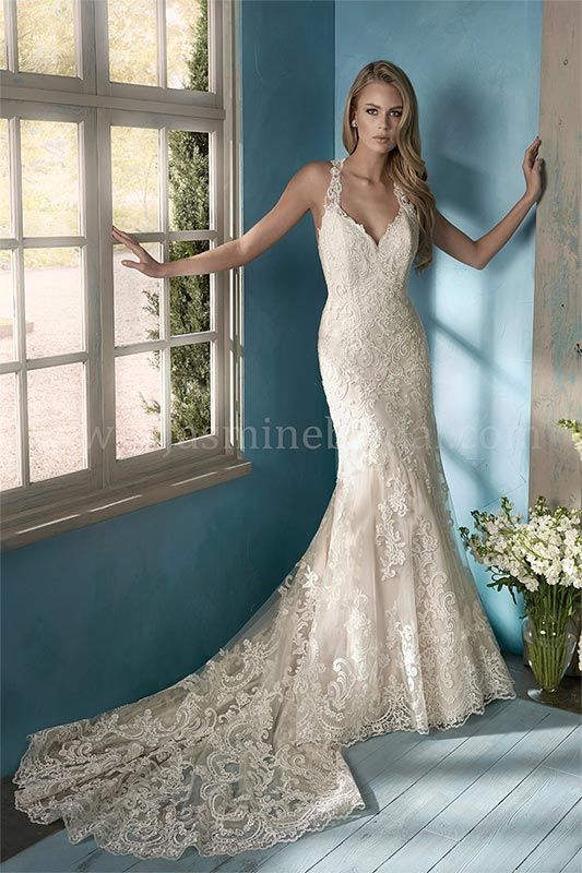Woman in a lace white gown posing beside a window in a blue room