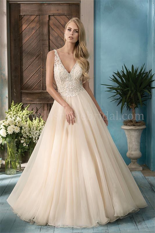 Woman in a cream tulle gown standing in a rustic indoor setting with blue walls and plants