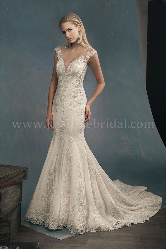 Woman in a white lace mermaid wedding dress posing against a blue backdrop