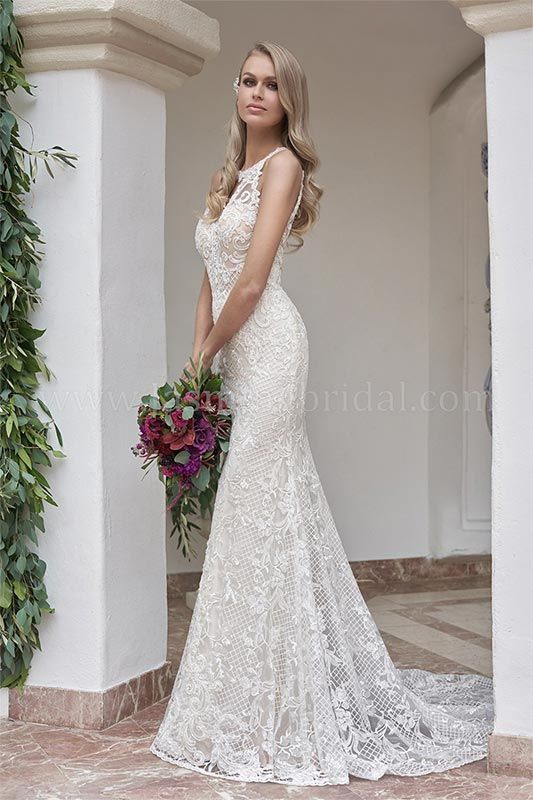 Woman in a white lace gown holding a colorful bouquet beside a white column outdoors