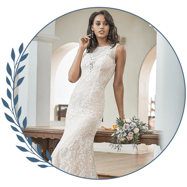Woman in a white lace dress posing indoors beside a bouquet in a circular floral frame
