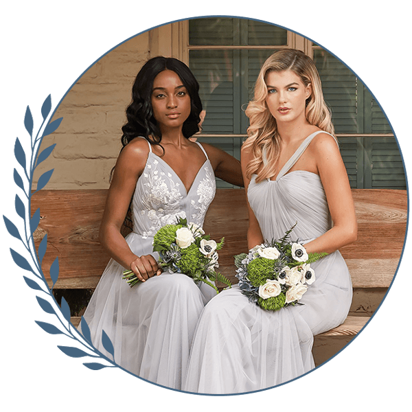 Two ladies in silver dresses holding white-and-green bouquets, seated in a circular photo frame.