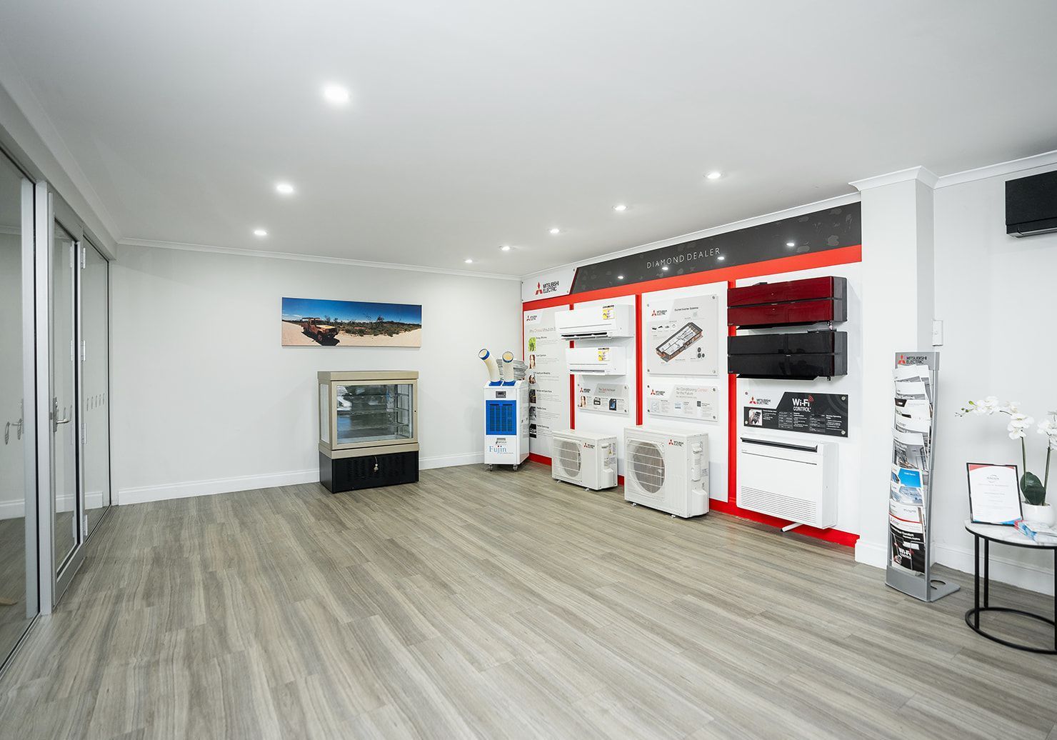 Empty showroom with air conditioning displays; white walls, wooden floor.