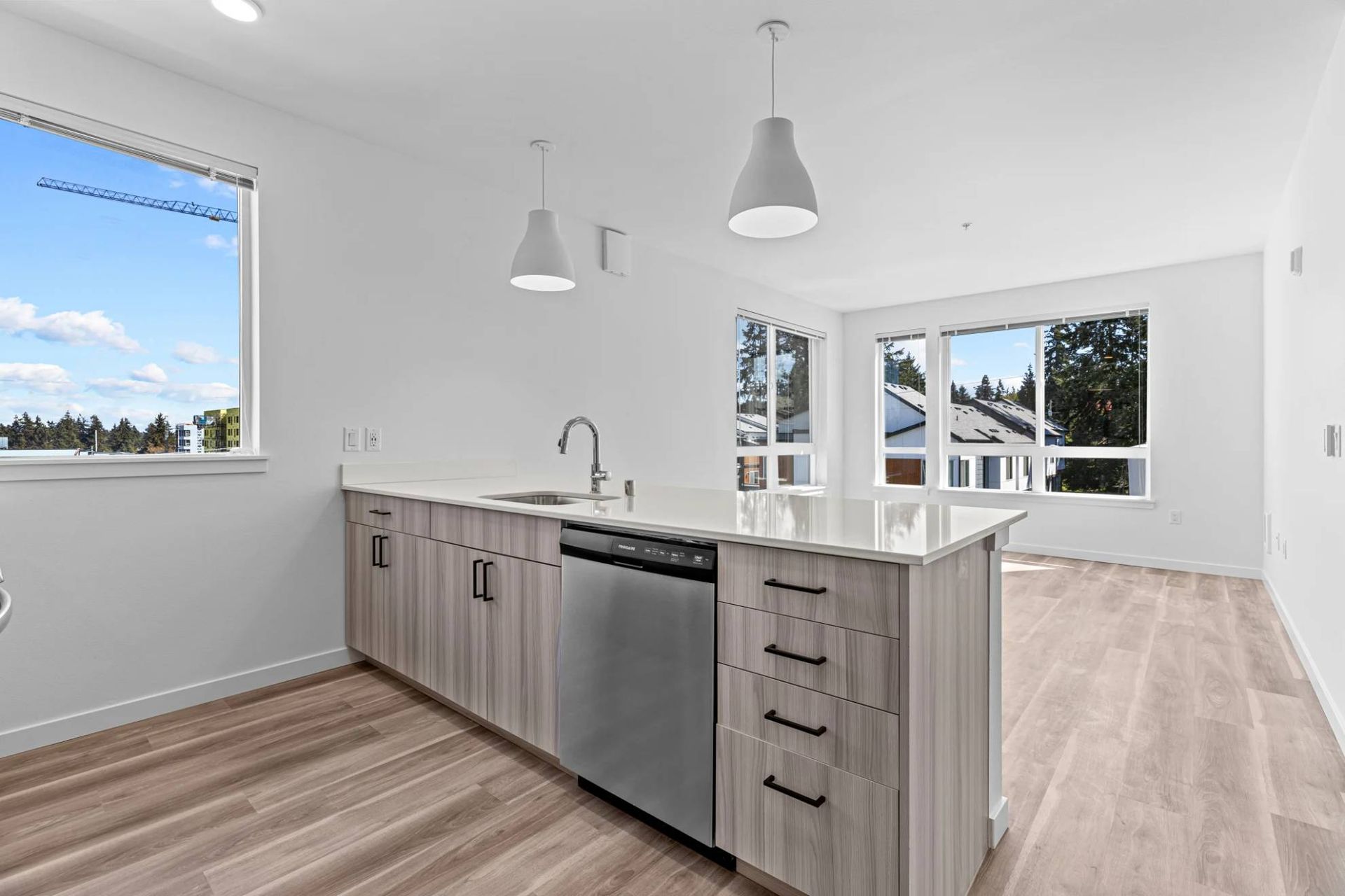 Bright modern kitchen with island, stainless dishwasher, and large windows at Zinnia Apartments in Shoreline, WA.
