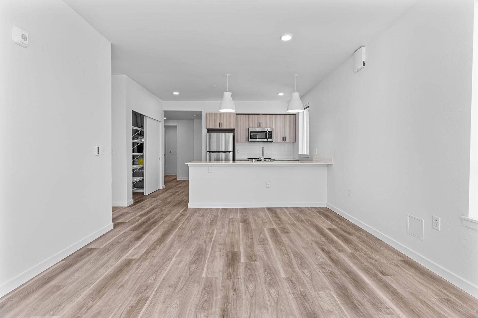 Open-concept kitchen with island and stainless appliances visible from living area at Zinnia Apartments in Shoreline, WA.