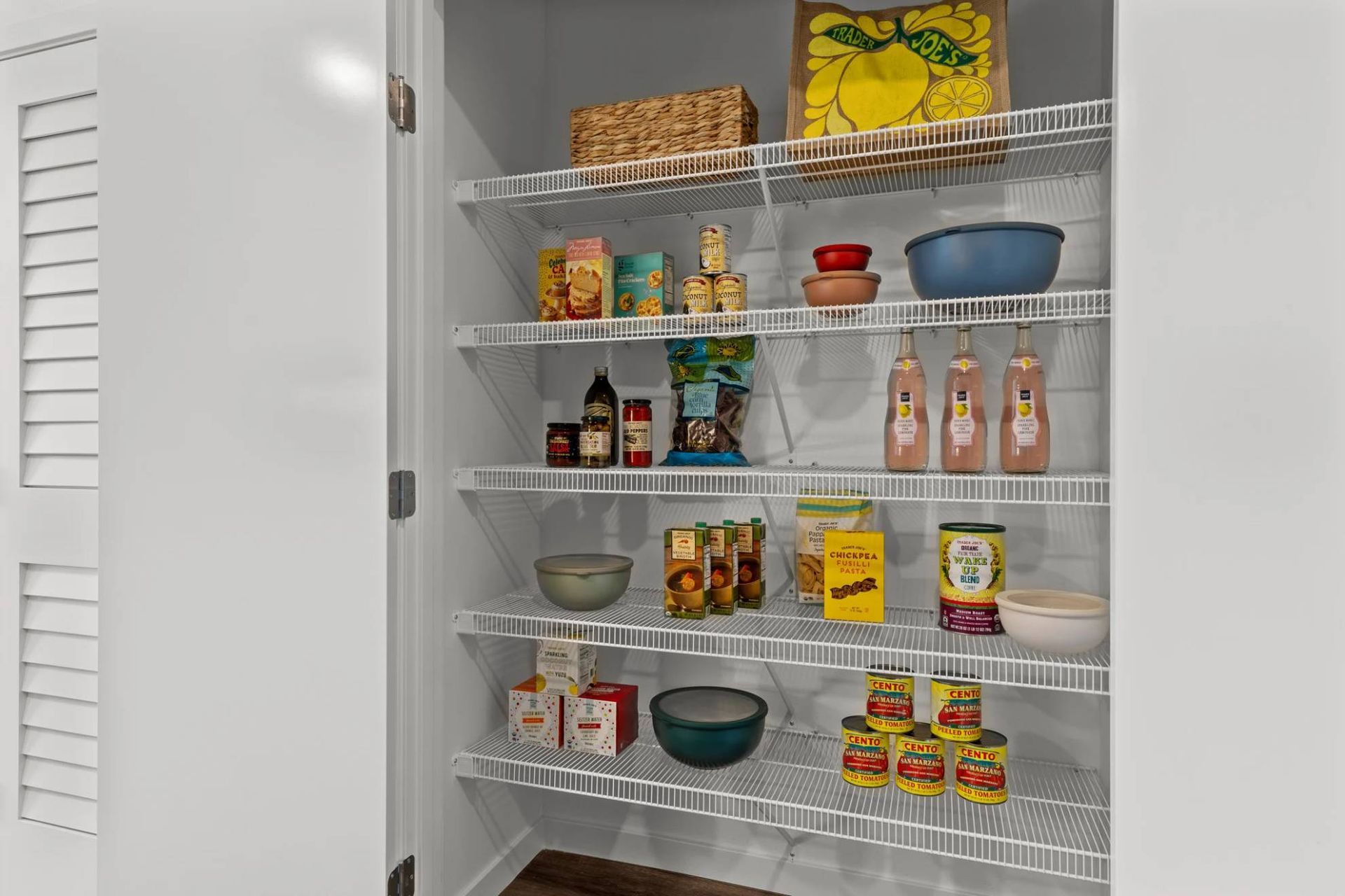 Pantry closet in an apartment with white wire shelves stocked with cans, boxes, and bottles at Zinnia Apartments in Shoreline, WA.