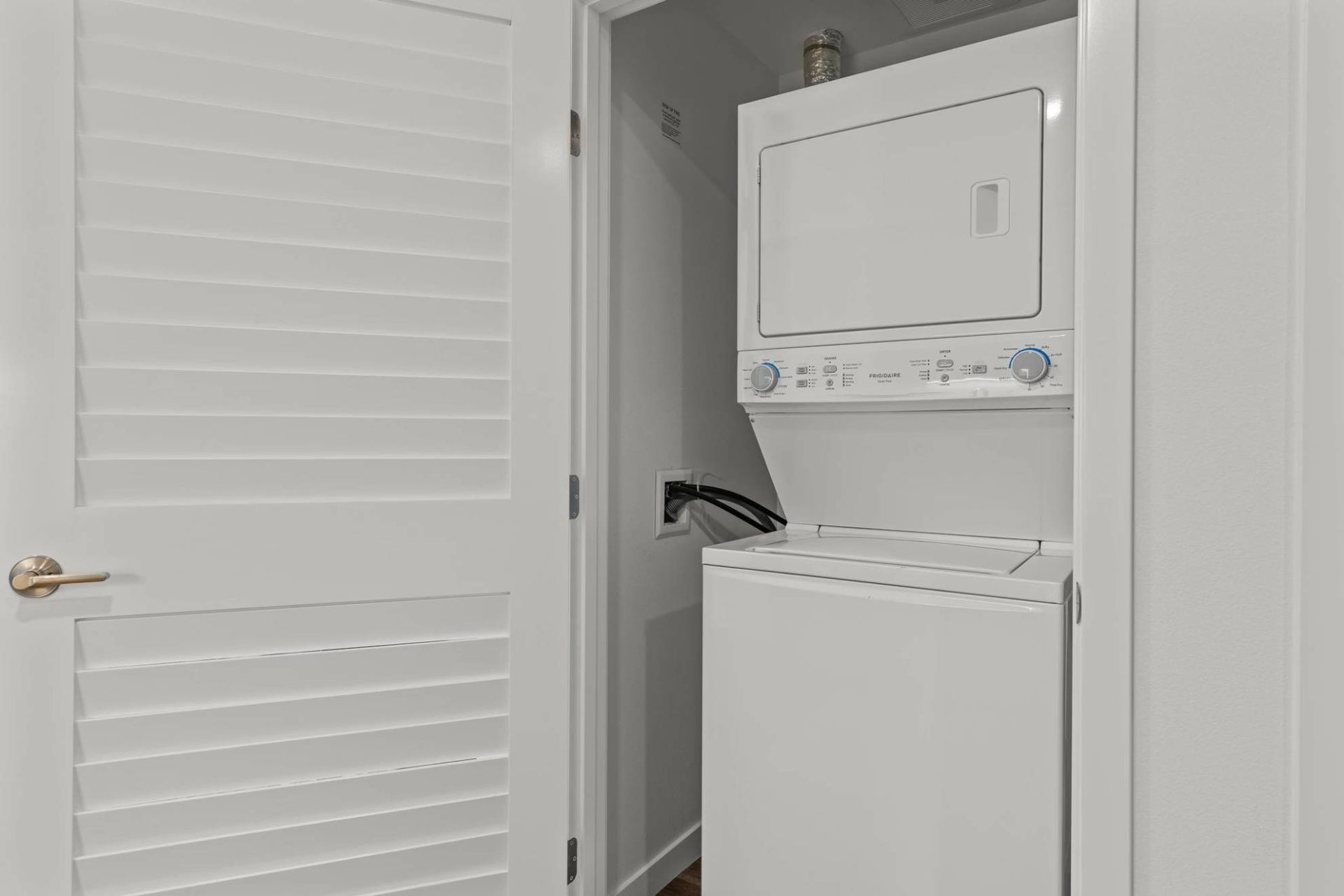 Stacked washer and dryer inside a closet with white louvered doors at Zinnia Apartments in Shoreline, WA.