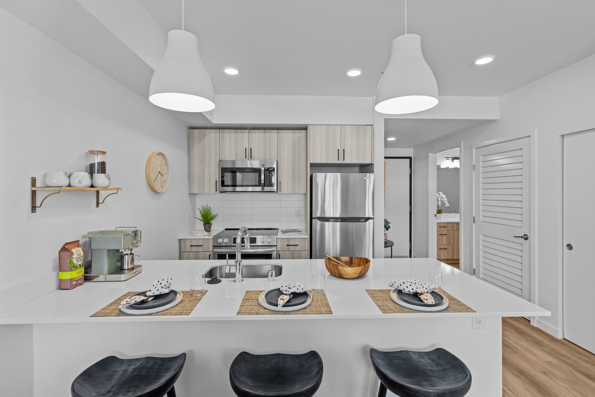 Modern apartment kitchen with an island, stainless-steel appliances, and light wood cabinets at Zinnia Apartments in Shoreline, WA.