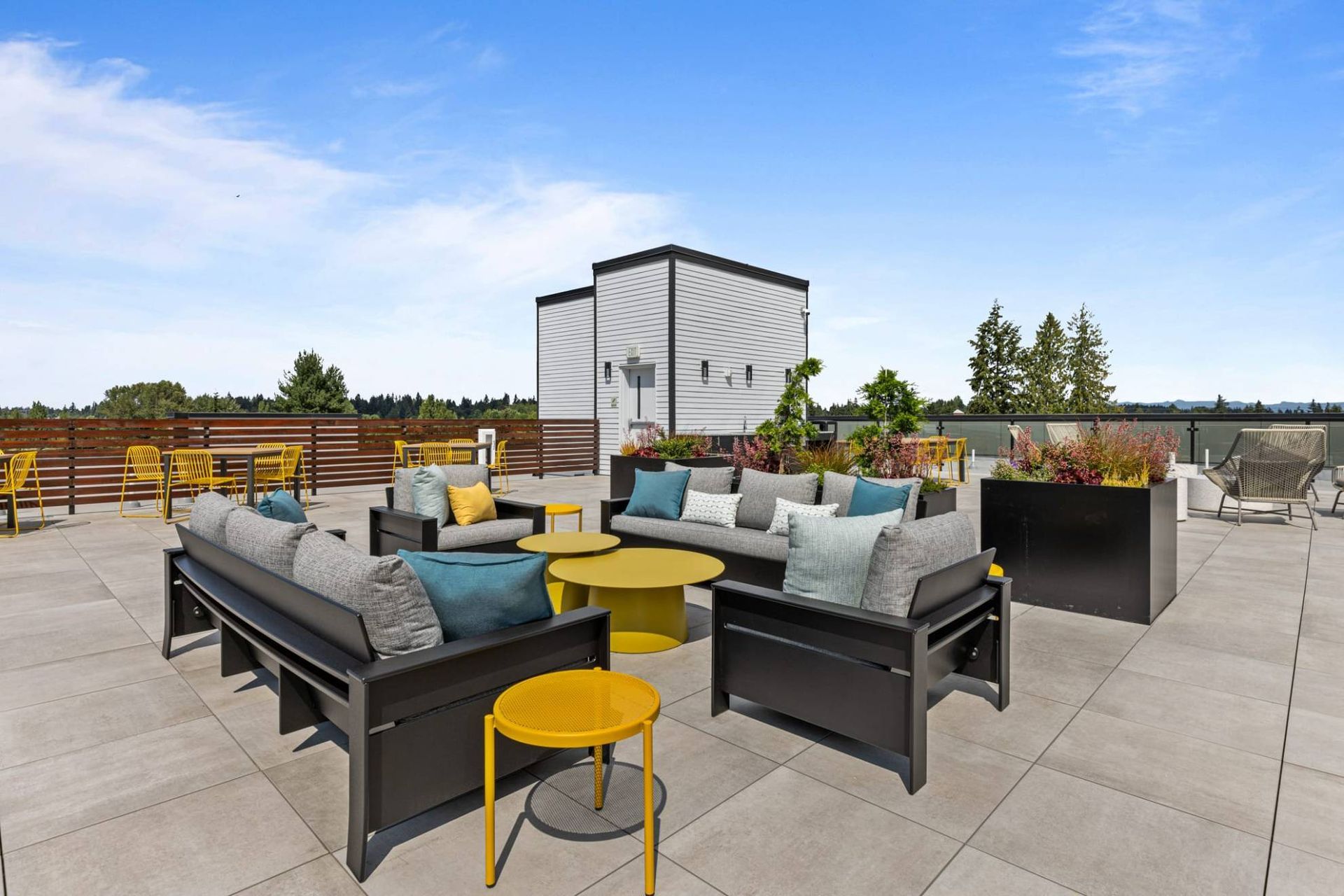 Rooftop terrace with modern outdoor seating, planters, and distant city views at Zinnia Apartments in Shoreline, WA.