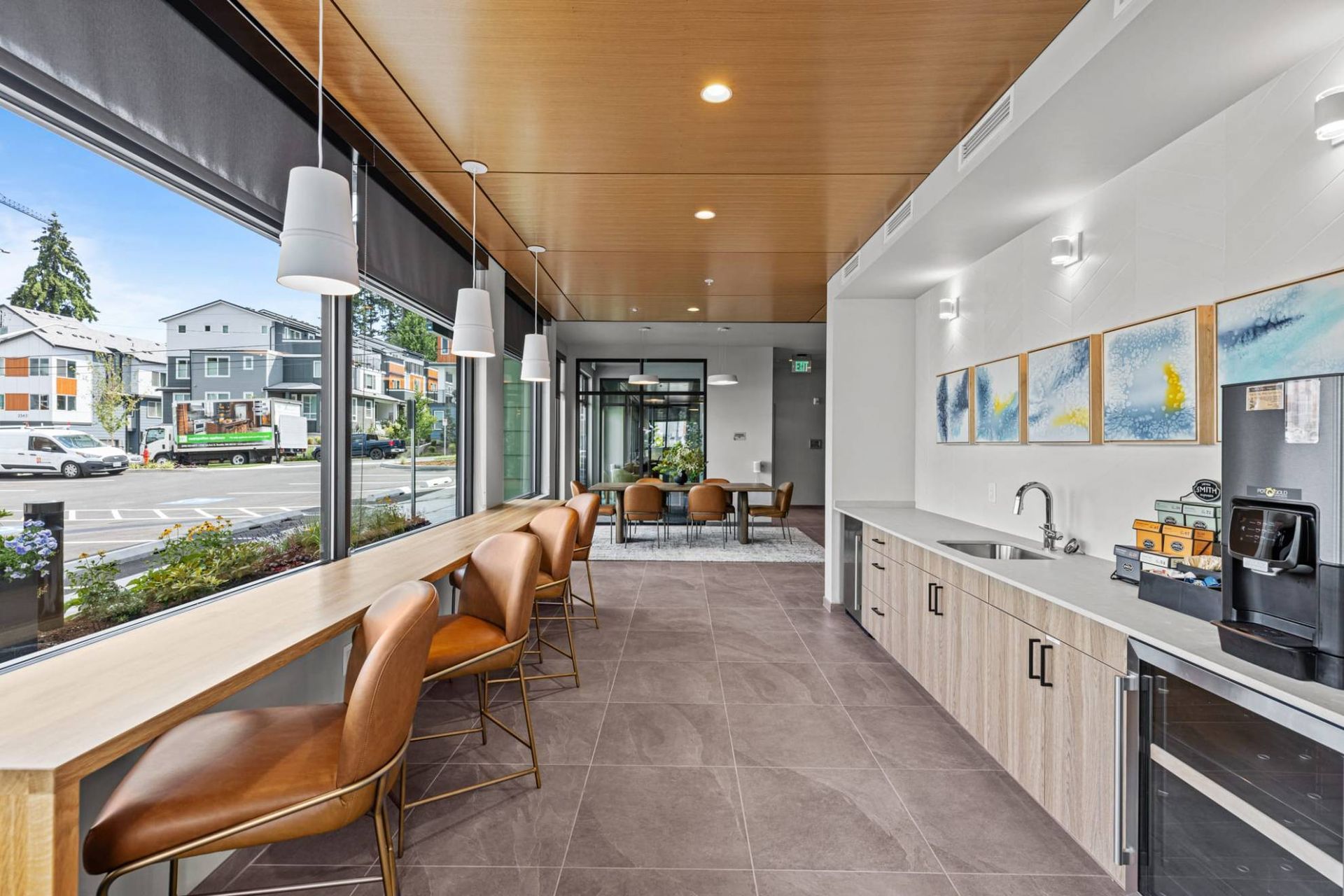 Bright community lounge with a long window counter and kitchenette at Zinnia Apartments in Shoreline, WA.