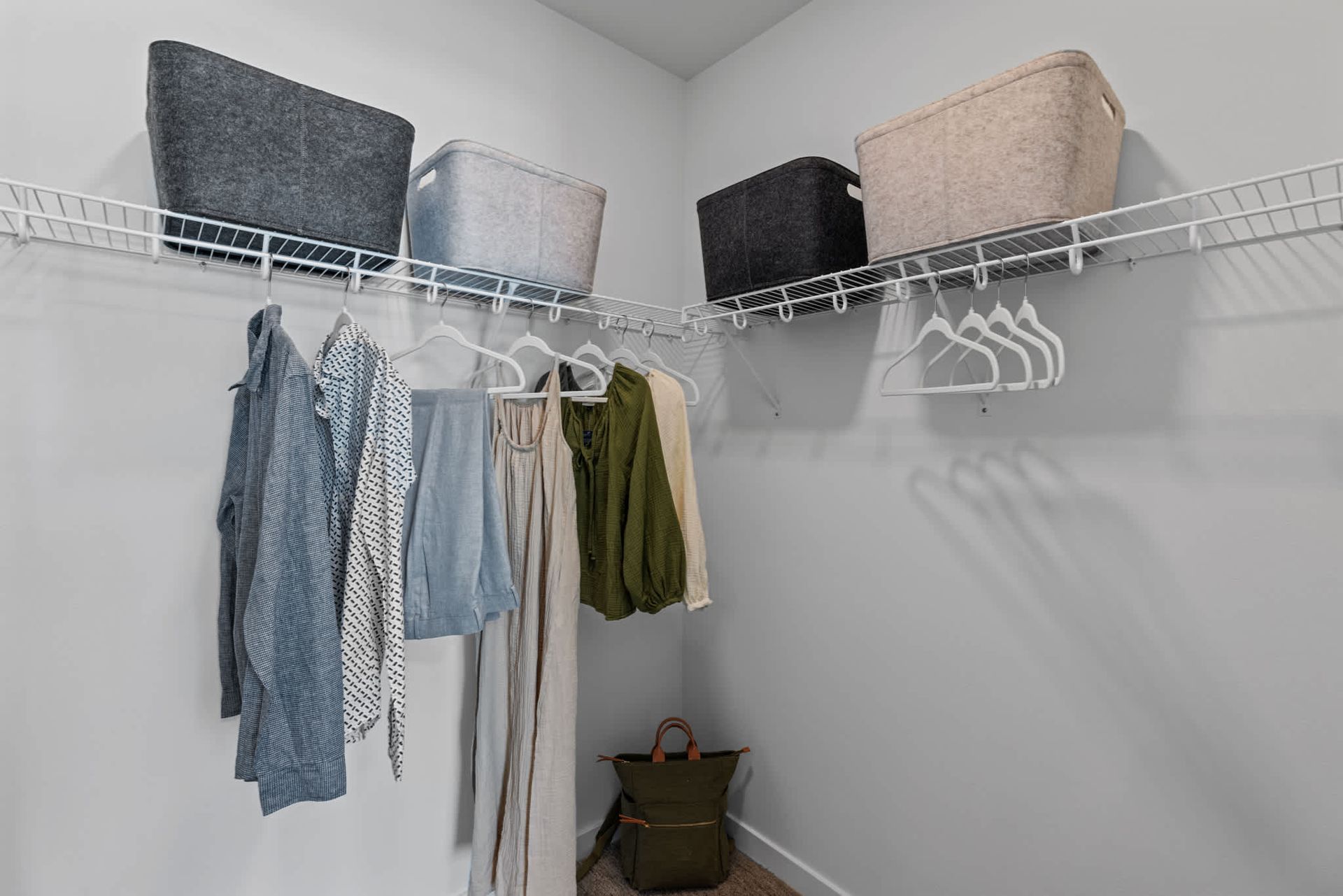 Walk-in closet with hanging clothes and wire shelving at Zinnia Apartments in Shoreline, WA.