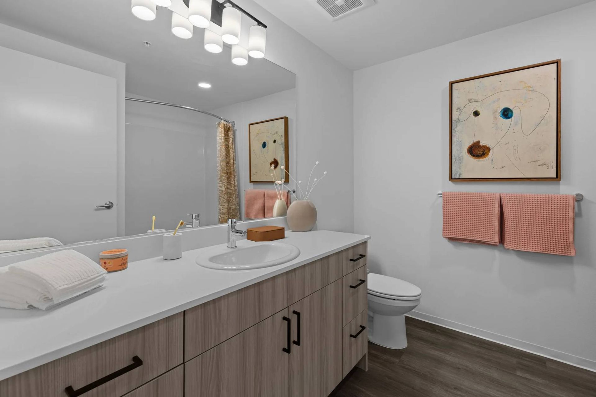 Modern apartment bathroom with double-sink vanity, large mirror, and pink towels at Zinnia Apartments in Shoreline, WA.