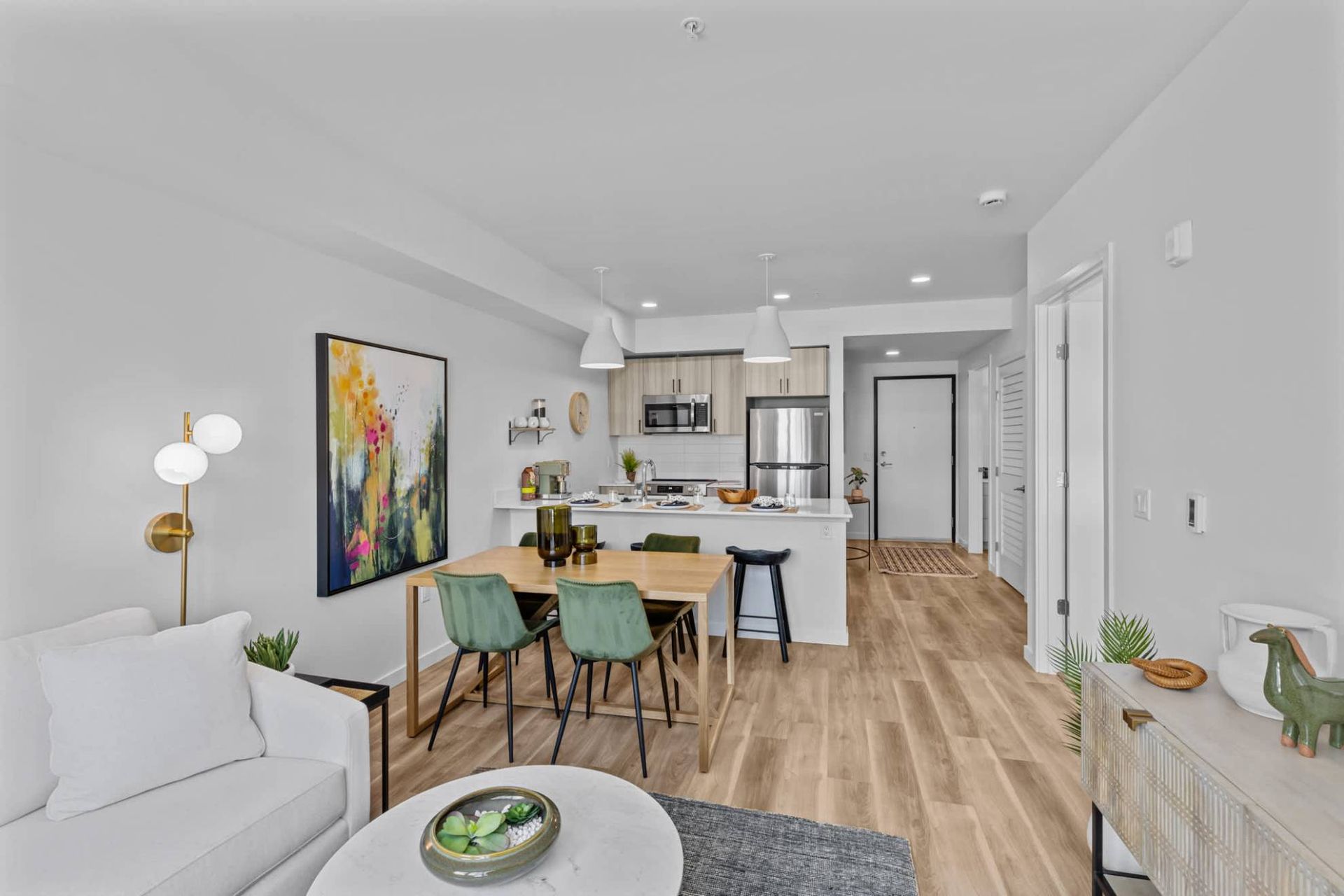 Open-concept living area with a dining table, kitchen island, and stainless-steel appliances at Zinnia Apartments in Shoreline, WA.