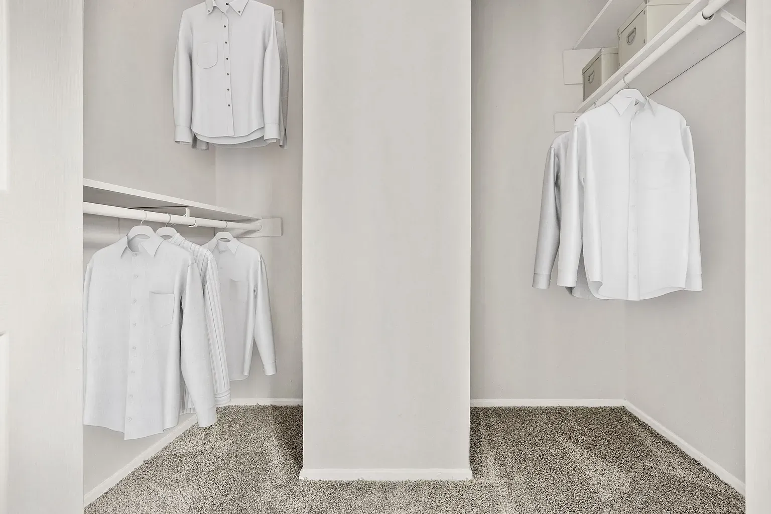 Open walk-in closet with white shirts on hangers and shelves.